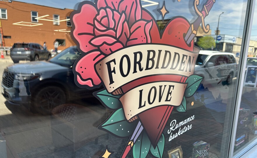 A window with an image of a heart with a sword running through it on a flower on top.