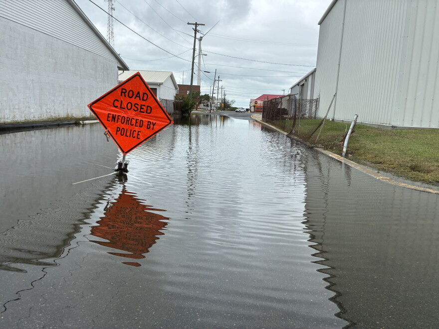 A flooded street with a "road closed" sign