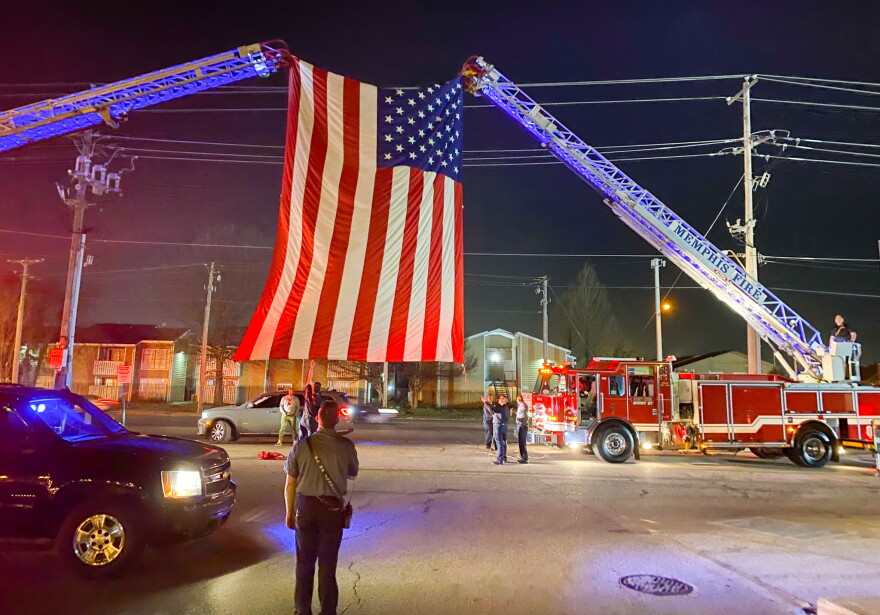Law enforcement's motorcade to honor Officer Geoffrey Redd passed below an American flag displayed as a tribute.