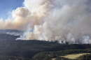 Smoke rising from a wooded foothills area.