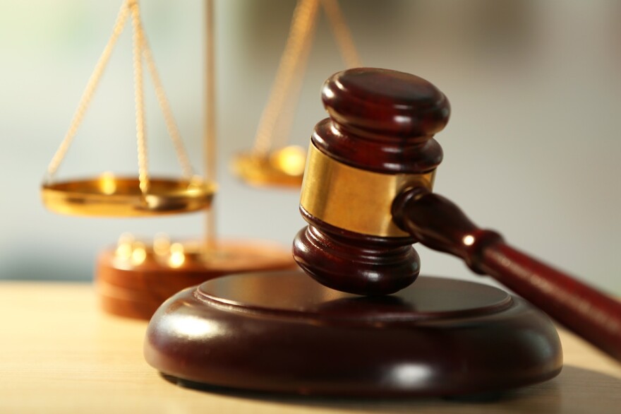 Wooden judge's gavel on a table with the scales of justice in the background