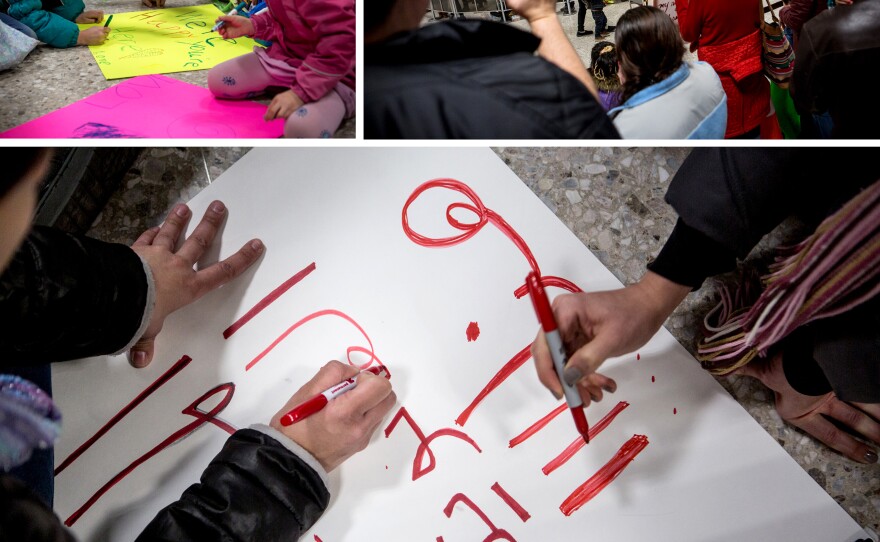 (Top left) Miranda Van Hemert, 11; Lori Stearns, 9; and Norah Van Hemert, 7, make signs on the floor of the international arrivals waiting area at Dulles International Airport. (Right) Demonstrators Dulles cheer passengers exiting international flights. (Bottom) Volunteers at Dulles make a sign in Arabic on Sunday, which reads "free legal help."