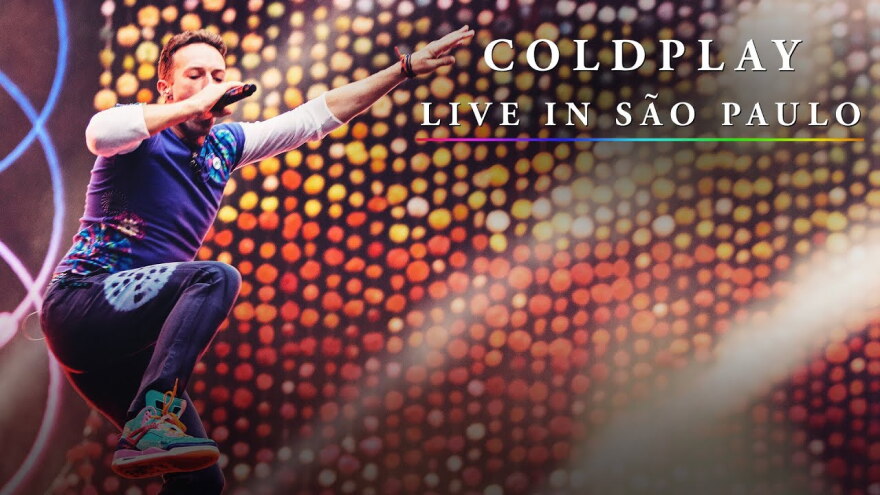 Chris Martin, lead singer jumps in the air next to words "Coldplay: Live from São Paulo"
