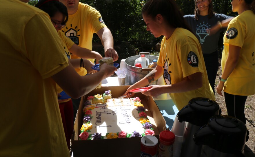 AmeriCorps volunteers cut into the cake celebrating Lou Alice James' upcoming return to her flood-damaged home.