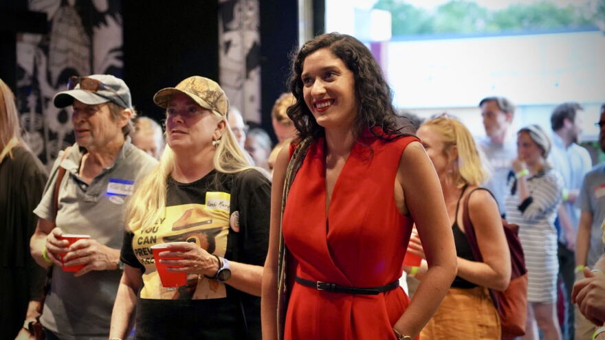 A woman dressed in red stands among a crowd