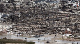 People walk near the remains of burned homes after Hurricane Sandy in the Breezy Point neighborhood of the Queens borough of New York City on Oct. 31, 2012. Over 50 homes were reportedly destroyed in a fire during the storm.