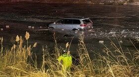 A member of the Ohio Township Fire Department approaches a vehicle that ran off a Warrick County road and trapped the driver in an icy pond