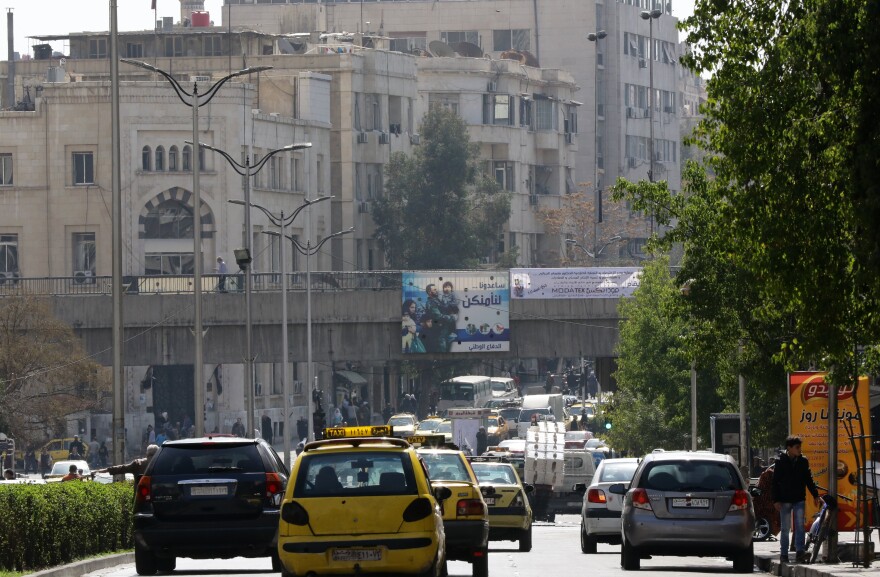 Syrians drive past government billboards in the capital of Damascus on Saturday, as a partial cease-fire — the first major truce of the five-year war — takes hold. Guns fell silent at midnight in suburbs around the capital and the bomb-scarred northern city of Aleppo.