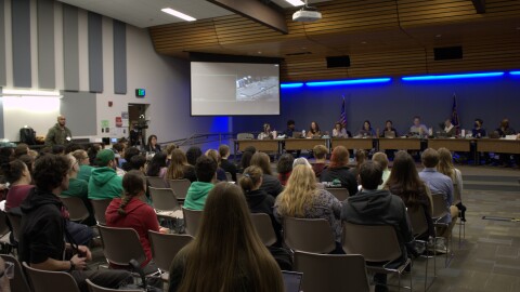 A crowd sit in a meeting room.