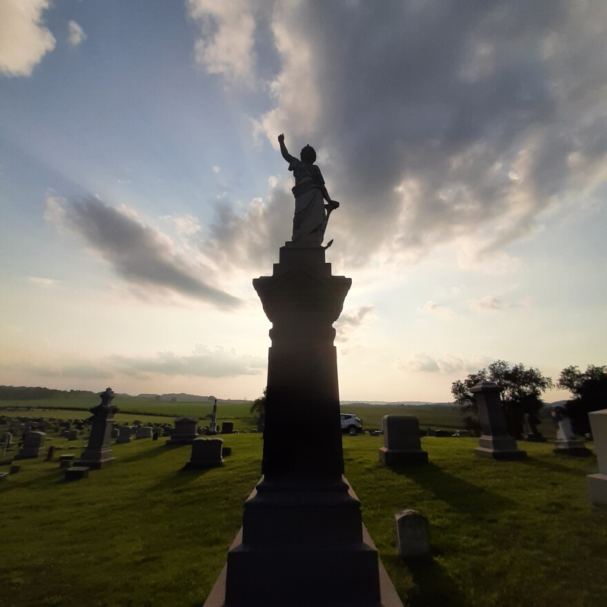 Headstones in a cemetery with a sunset in the background.