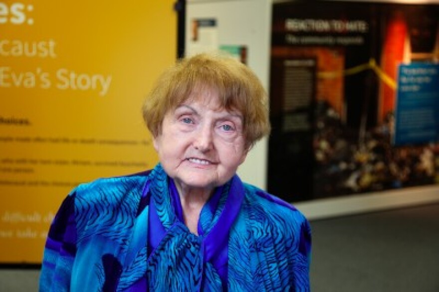 Older woman posing in front of a poster.