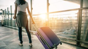 Young woman pulling suitcase in airport terminal. 