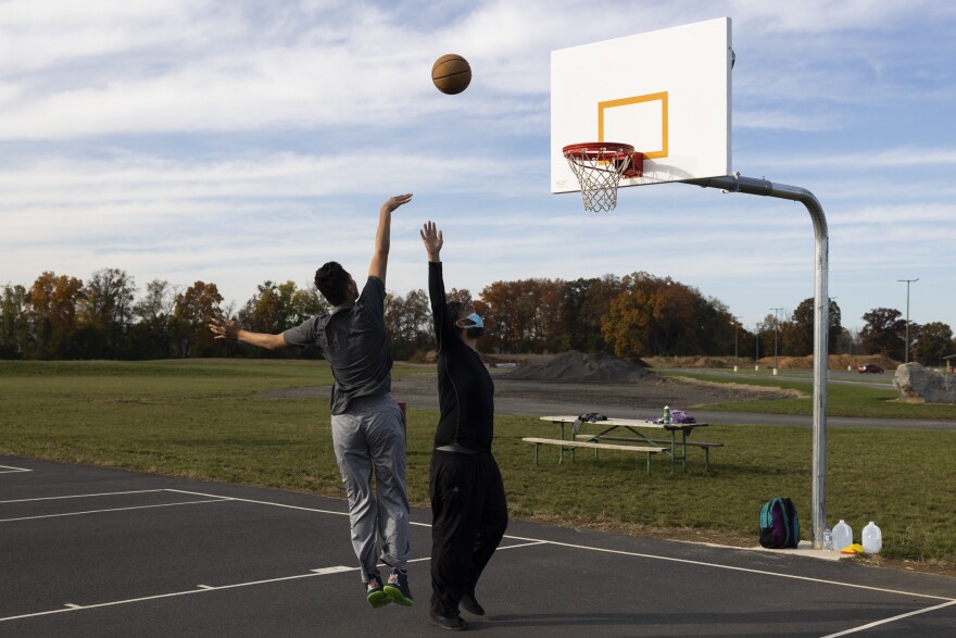 Alex runs basketball drills with his sons at the park to prepare them for team tryouts.