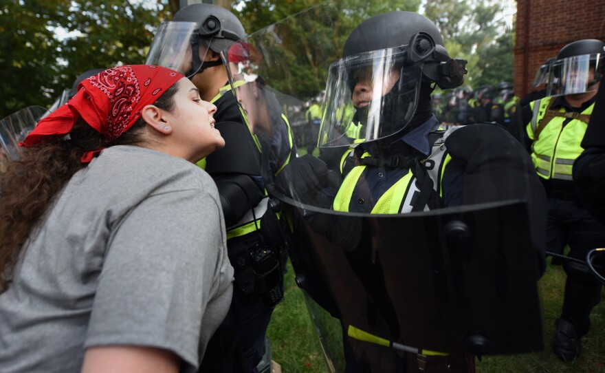 A woman repeats over and over, "They are just students. You are scaring them," to riot-clad police at UVA where students and others are gathered in protest.