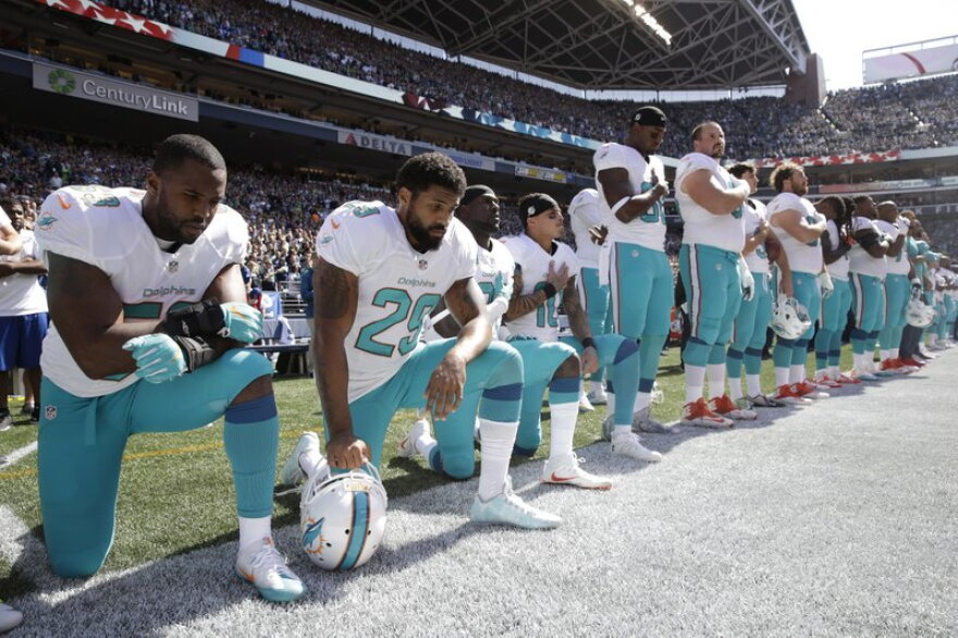 From left, Miami Dolphins' Jelani Jenkins, Arian Foster, Michael Thomas, and Kenny Stills, kneel during the singing of the national anthem before an NFL football game against the Seattle Seahawks in Seattle, on Sept. 11, 2017.