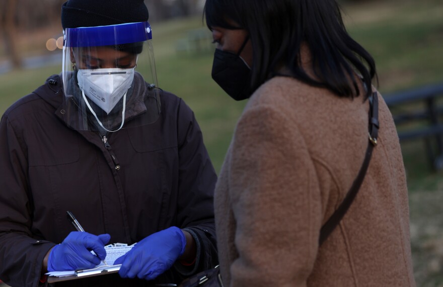 COVID-19 test site lead Nardos Amare checks in a patient for a COVID test outside Benning Stoddert Recreation Center on Dec. 23 in Washington, D.C.