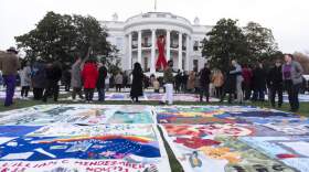 AIDS survivors, their families and advocates look at the display of AIDS Memorial quilts spread over the South Lawn of the White House during a ceremony to commemorate World AIDS Day, Sunday, Dec. 1, 2024, in Washington. (Manuel Balce Ceneta/AP)