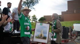 Lawrence, Kansas, artist Stan Herd, at left, accepts a signed, framed photograph from the Algerian community as a thanks for his flag art on June 13.