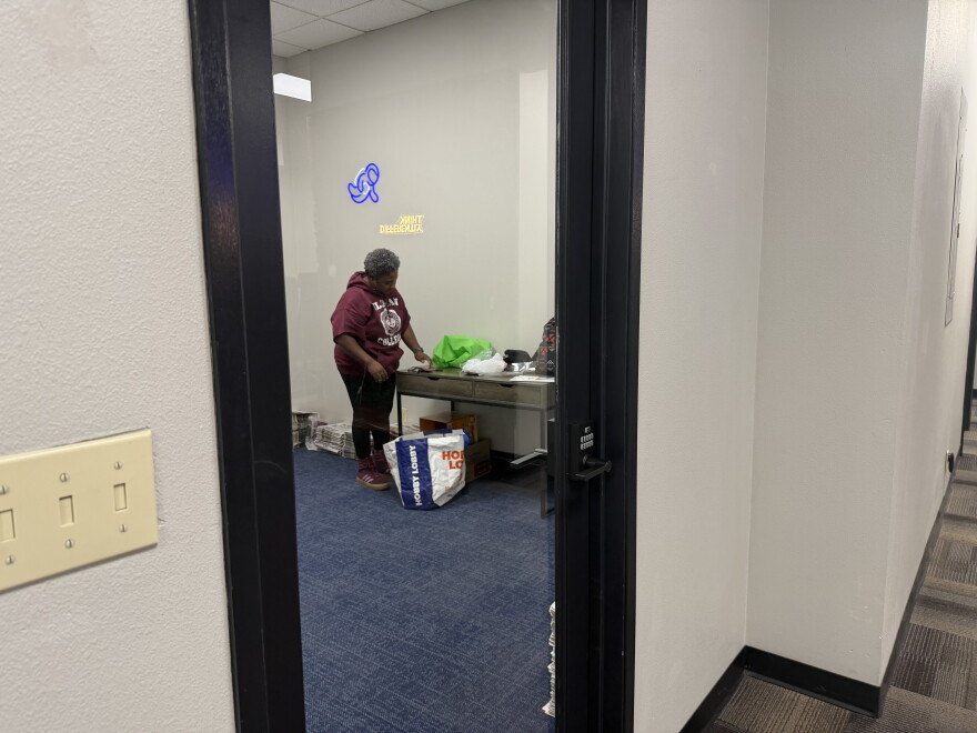 A woman in an almost empty office unpacking newspapers from a bag.