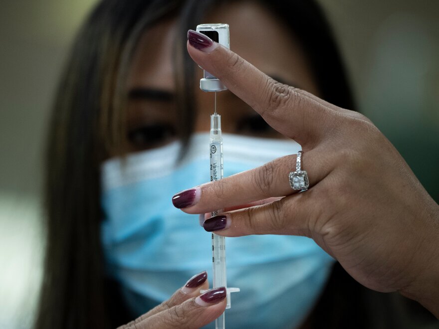 A pharmacist dilutes the Pfizer COVID-19 vaccine while preparing it to administer to staff and residents at the Goodwin House Bailey's Crossroads, a senior living community in Falls Church, Virginia, on December 30, 2020. (Photo by Brendan Smialowski / AFP) (Photo by BRENDAN SMIALOWSKI/AFP via Getty Images)