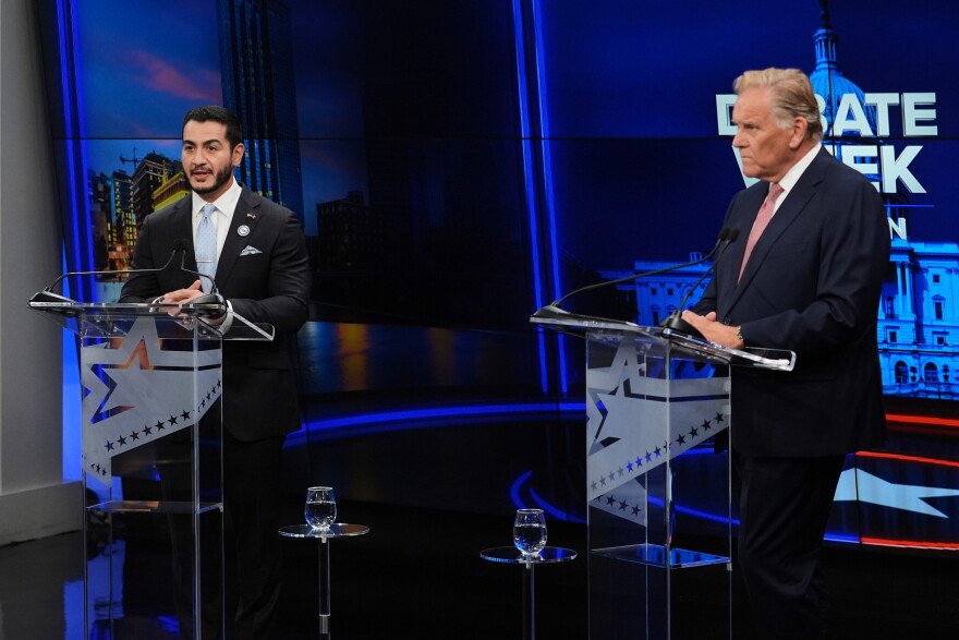 Republican nominee for U.S. Senate Mike Rogers, right, faces off against Democratic nominee for U.S. Senate Abdul El-Sayed on a debate stage at podiums.