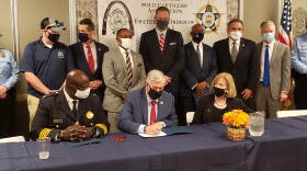 St. Louis Metropolitan Police Chief John Hayden, Mayor Lyda Krewson and other state and local leaders watch Thursday as Gov. Mike Parson signs legislation eliminating the residency requirement for public safety employees in St. Louis, including police officers.