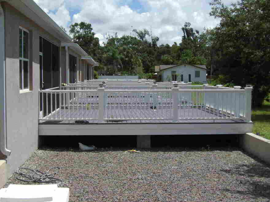 The back of a home showing a raised porch, with a line of similar house and porches behind this one