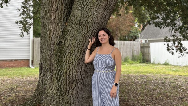 Elizabeth Burrows stands with a live oak tree on a vacant lot next to her home in Norfolk's Park Place, on June 16, 2026.