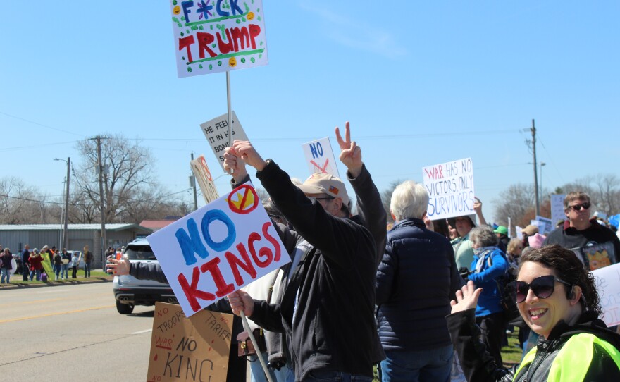 Protesters wave to passings cars with signs that read "No Kings" and "F*ck Trump" 