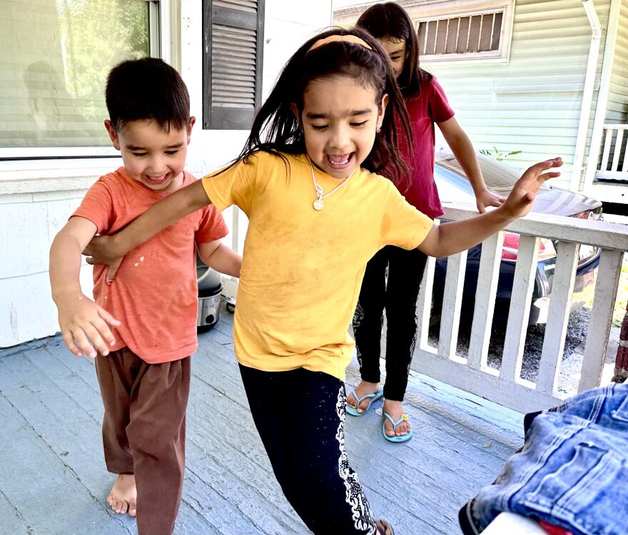 Children playing on a porch. 4-year old Nasrin Karin Yar playing with her brother Abdul Rahman and sister Nasiba