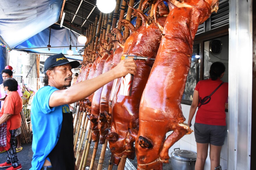 Jesus Robles torches the remaining hair off roasted pigs. <em>Lechon</em>, or roasted pig, is a regular fare at Philippine festivities, especially during Christmas and New Year celebrations.