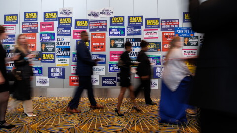 People walk by a wall that is plastered with campaign signs