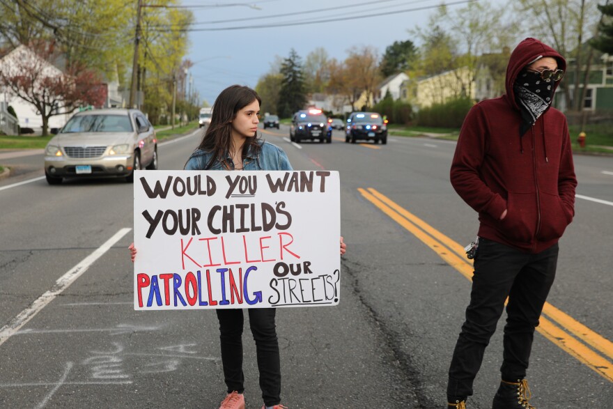 Jazmarie Melendez, whose 15-year-old brother Jayson Negron was killed in a 2017 police shooting in Bridgeport, holds up a protest sign during Thursday's march in Wethersfield.