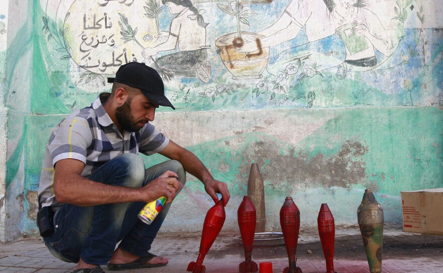 A rebel with the Free Syrian Army spray paints improvised mortar shells at a weapons factory in Aleppo on Thursday.