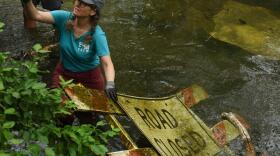 Laura Semken works to lift a large sign out of Flat Branch Creek on Wednesday at the MKT Nature and Fitness Trail in Columbia. Semken, a member of the Missouri River Relief crew, said the creek is "near and dear to my heart." She has been helping maintain the area since moving to Columbia in 2019.