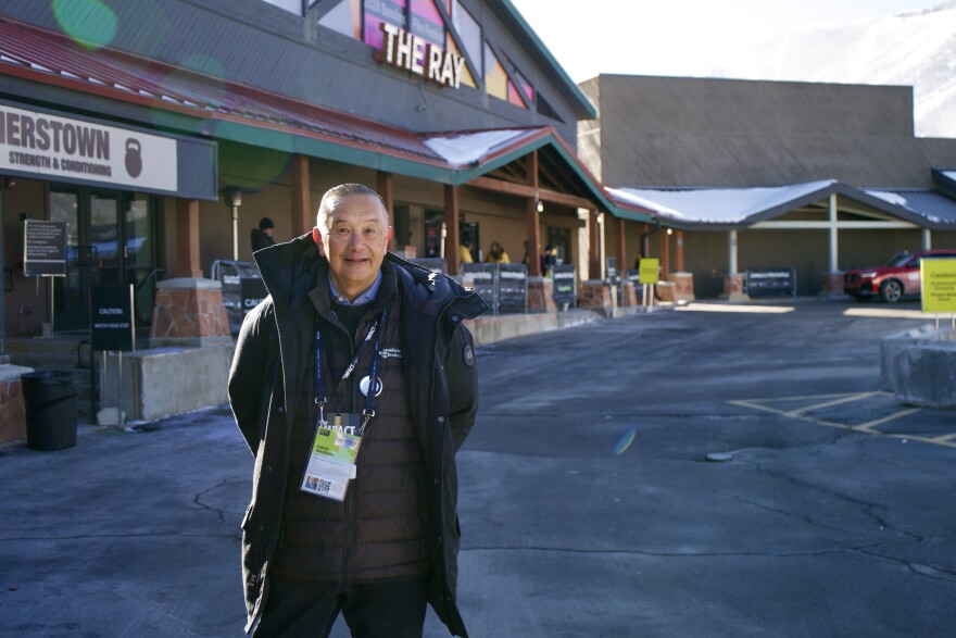 A man with a festival pass poses in front of a theater.