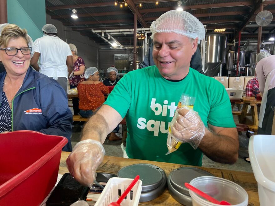 Paul Larocco, volunteer from Bite Squad, weighs each bag of macaroni. Larocco sees the value in giving back to the community. Becky Raymond, owner and volunteer from SERVPRO, watches in the background. (Dana Bryan/WUFT News)