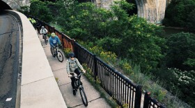 People bike along an off-road trail above the Genesee River