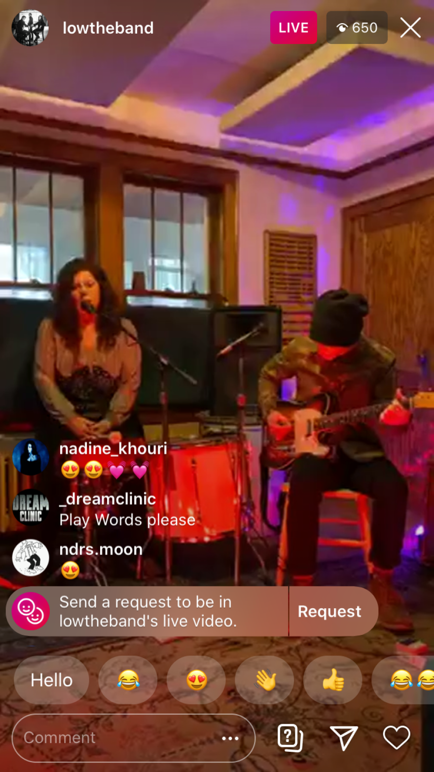 Woman behind the drums singing and a man playing guitar