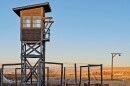 A wooden guard tower standing in a wheat field.