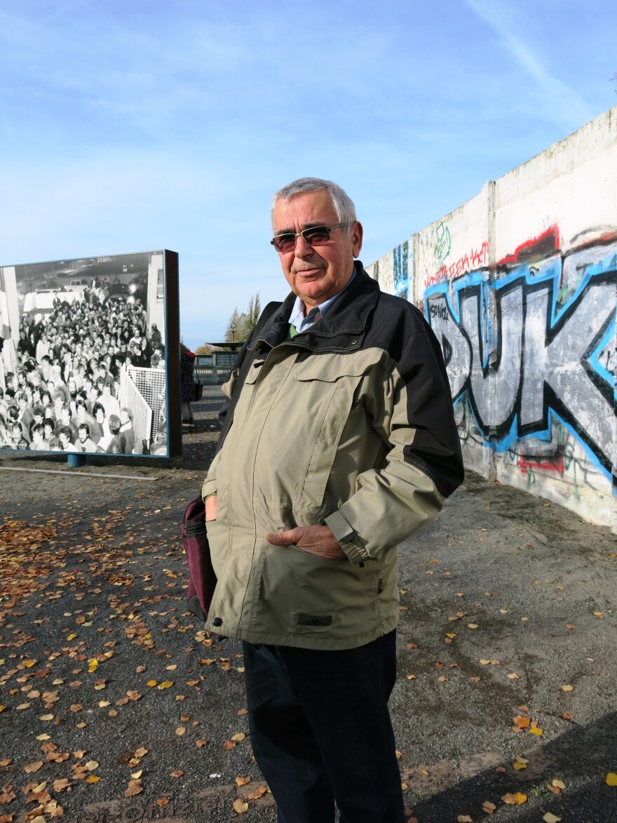 Jaeger stands in front of a remnant of the Berlin Wall. Behind him is a photo from Nov. 9, 1989, when he was the border guard who opened up the Bornholmer Street crossing, allowing East Germans to go to the west, the event that marked the fall of the wall.