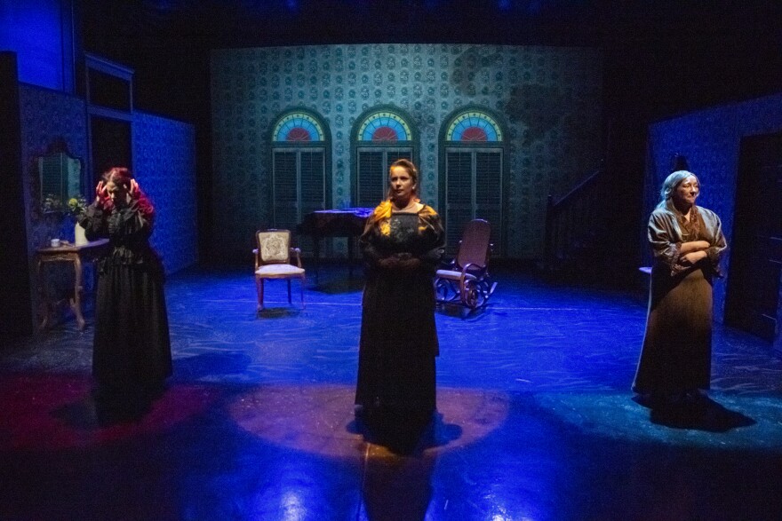 Three women stand center stage with mood lighting during a performance of "Los Soles Truncos" at the LatinUS Theater. 