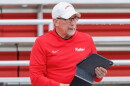 Older man in a red hoodie and white hat holding a computer tablet in his left hand.