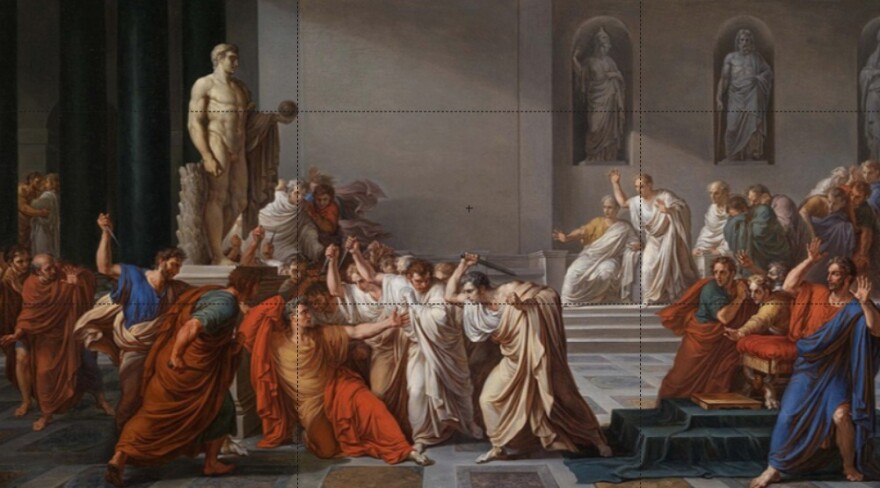 A classical-style painting depicting the assassination of Julius Caesar inside a grand Roman hall, where a group of senators in flowing robes surround and stab him as others react in shock; marble statues and columns frame the dramatic scene.
