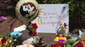 A sign that reads "Forever Stands Unconquered," is placed among flowers near the Florida State Student Union building, Tallahassee, Fla., Friday, April 18, 2025. (AP Photo/Gary McCullough)