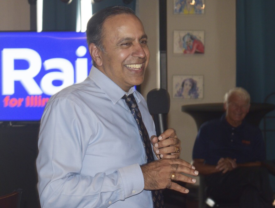 A man in a shirt and tie talks to a room of politically active people