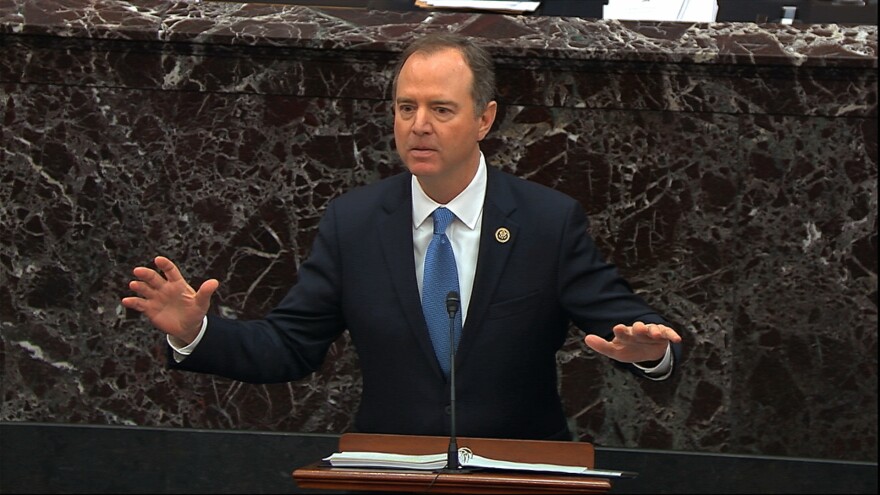 Adam Schiff stands at a podium holding his hands above the surface of the table.