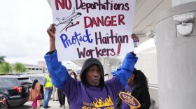 African American man holds sign saying No Deportations, Danger, Protect Haitian Workers 