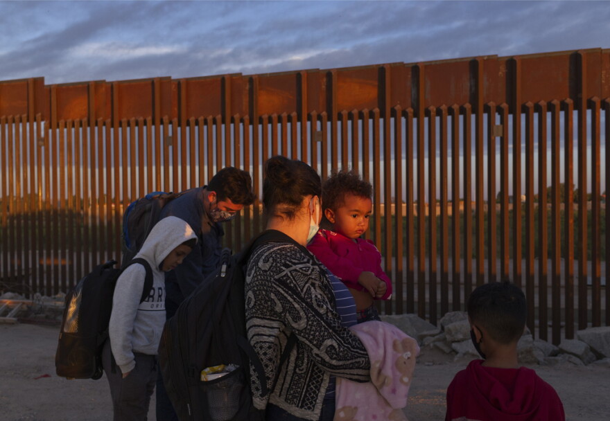 FILE - A pair of migrant families from Brazil wait to be processed by U.S. Border Patrol agents after passing through a gap in the border wall from Mexico in Yuma, Ariz., Thursday, June 10, 2021, to seek asylum. A federal judge was poised Friday, Dec.8, 2023, to prohibit separation of families at the border for purposes of deterring immigration for eight years. (AP Photo/Eugene Garcia, File)