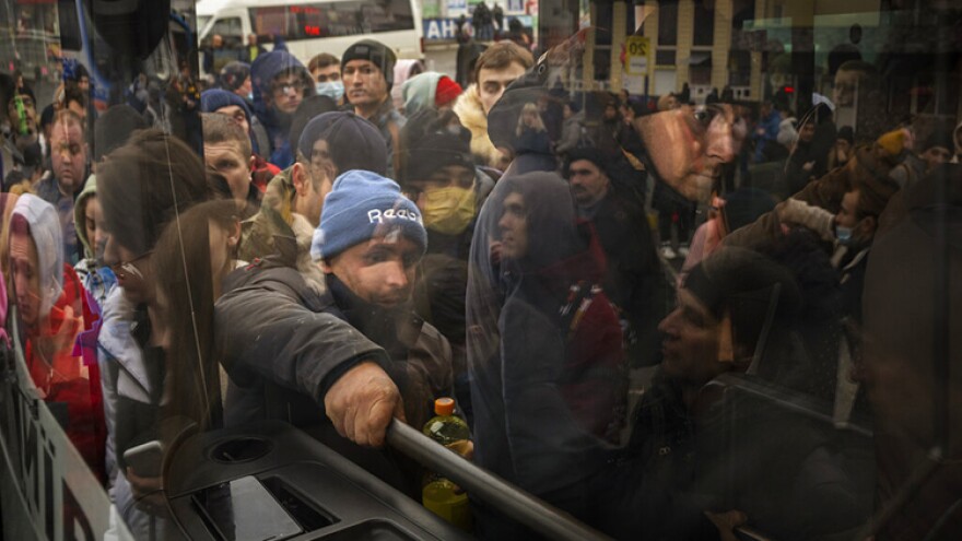 People try to get on a bus as they leave Kyiv, Ukraine, Thursday, Feb. 24, 2022. Russia launched a wide-ranging attack on Ukraine on Thursday, hitting cities and bases with airstrikes or shelling, as civilians piled into trains and cars to flee.